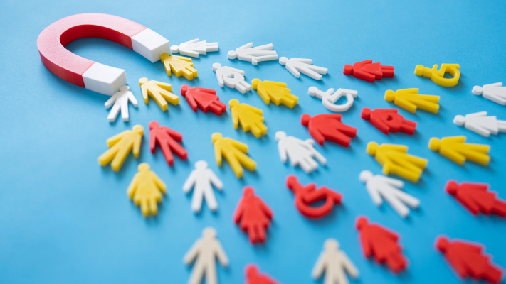 large red horseshoe magnet attracting a variety of colored figures, suggesting the concept of attraction or retention, likely in a business or marketing context.